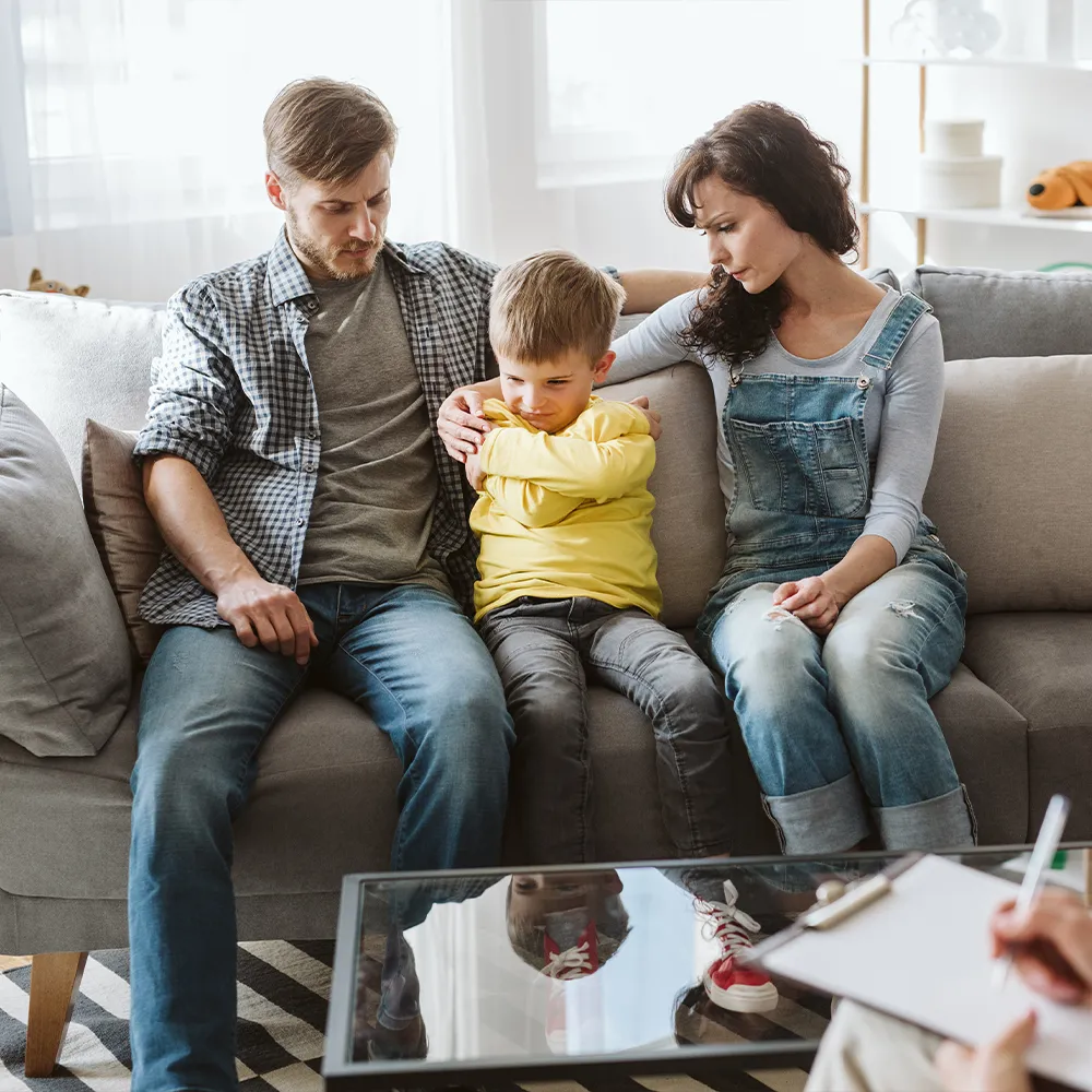 Family therapy - mother and father attending family therapy with upset looking child